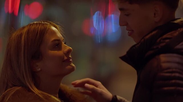 A young couple in Paris share a romantic moment at night They are looking at each other with love and affection illuminated by the city lights The camera is handheld creating an intimate and personal 