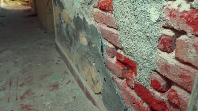 Peeling plaster falling off an old red brick wall