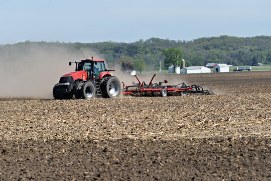 Red tractor  Pulling a  Double Fold Cultivator for spring field preparation.