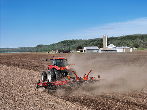 Red tractor  Pulling a  Double Fold Cultivator for spring field preparation.