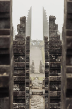View of the tiered stone gates of Cetho Temple leading through a misty pathway with traditional Hindu architecture in Kecamatan Jenawi, Jawa Tengah, Indonesia.