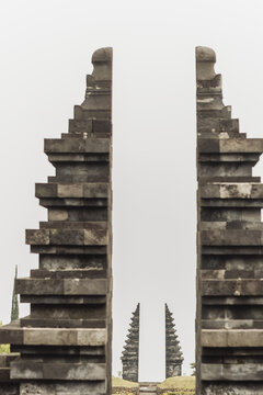 View of the iconic split gateway of Cetho Temple with its traditional stone masonry under a misty sky in Kecamatan Jenawi, Jawa Tengah, Indonesia.