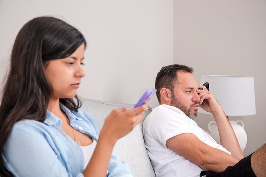 Family Members Using Smartphones While Sitting Together On Couch
