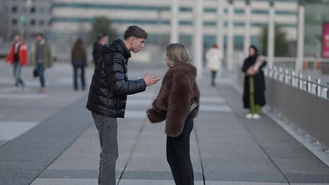 A young couple is arguing in Paris France The man and woman are in disagreement on a city square The scene depicts relationship problems conflict emotional distress frustration and anger.