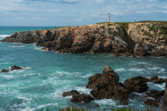Dramatic Coastal Landscape with Lighthouse on Cliff Overlooking Turquoise Ocean Waves and Rocks. Porto Covo, Setubal, Portugal