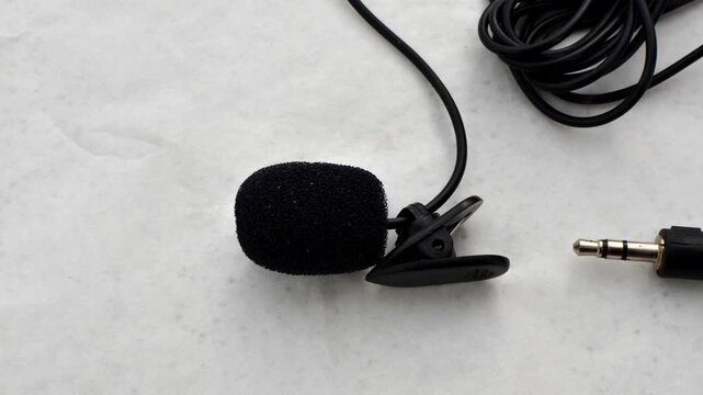 Close-up of lavalier microphone on smooth surface, ready to capture audio with elegance and precision.
