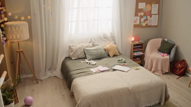 Pan full no people shot of cozy well-equipped kids bedroom interior with ballet barre and toys and notebooks on comfortable bed