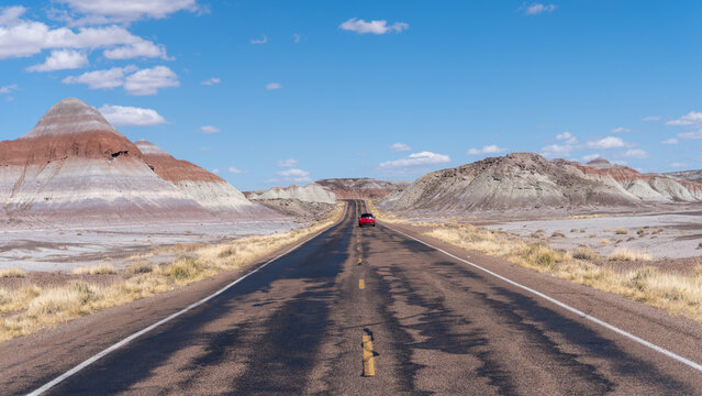 Petrified Forest National Park in Arizona. Car traveling on Petrified Forest Road through The Tepees, conical hills with banded mudstones resembling Tipis or Male Hogans.
