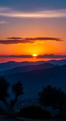 Obraz premium Vibrant Orange Sunset Glowing Over Layered Mountain Silhouettes