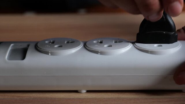 Close-up footage of a hand pulling an electrical plug out of a white multi-outlet power strip. Perfect for energy saving, power off, safety, and electricity concepts.pt