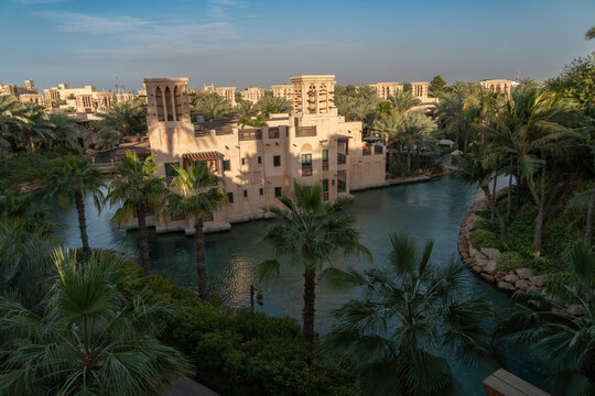 View of traditional Arabic architecture with wind towers and lush palm trees along a canal at the Madinat Jumeirah, Dubai, Dubai, United Arab Emirates.