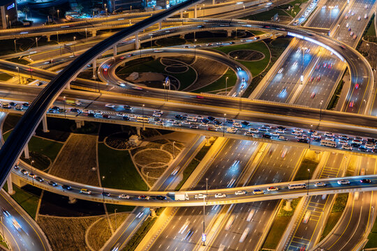 View of a complex multi-level highway interchange at night with light trails from moving vehicles and illuminated circular ramps in Dubai, Dubai, United Arab Emirates.