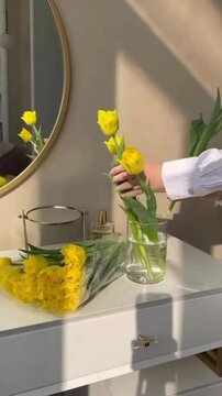 Placing Yellow Tulip Flowers One by One into Clear Glass Vase, Elegant Floral Arrangement and Aesthetic Home Decor