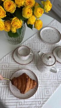 Elegant Morning Breakfast Preparation with Pouring Tea, Fresh Bread, Strawberries and Blackberries, Yellow Flowers in Vase and Aesthetic Plate
