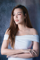 Fototapeta premium Beautiful Asian woman in white bodycon dress posing in studio, elegant fashion portrait with soft lighting and natural beauty.