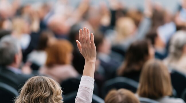 Woman raising hand in audience during seminar or conference