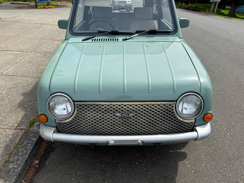 Headlights of vintage 1989 mint green Nissan Pao retro hatchback parked on a suburban Street. Bellingham, WA, USA - 30 April 2026