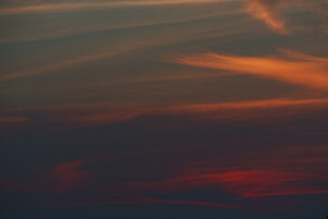 Fototapeta premium Intense fiery sunset clouds with dark blue sky during evening transition. Dramatic weather and atmosphere for creative use.