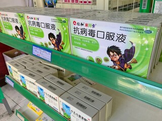 Naklejka premium LIJIANG, CHINA - OCTOBER 26, 2017:Boxes of antiviral oral liquid by Jen and Miaka Pharmaceuticals, a Chinese medicine for throat relief displayed on green shelves in a local pharmacy in Lijiang Yunnan