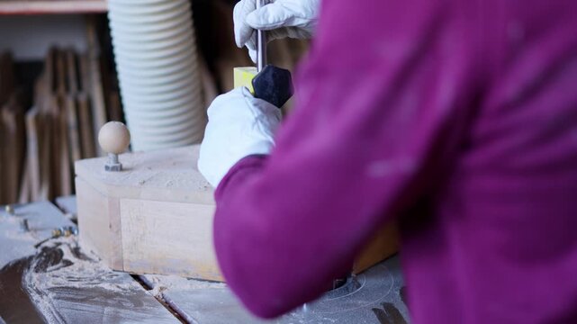 Worker shaping wood piece on edge banding machine