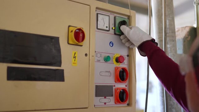 Operator hand turning on industrial machine control panel
