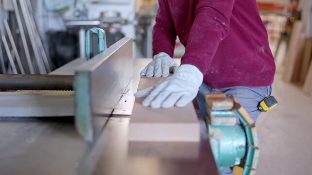 Carpenter planing a wooden board on a planer machine