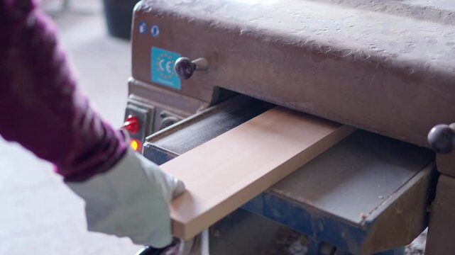 Carpenter sanding wooden plank with thickness planer,