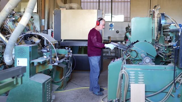 Carpenter operating an industrial wooden baluster sander machine