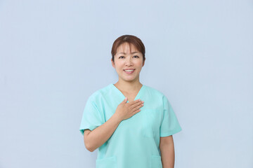 Fototapeta premium 笑顔で胸に手を当てる女性医療スタッフ
