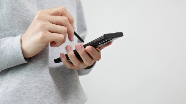Close up of hands using a foldable smartphone with stylus on white background, mobile technology, touchscreen interaction, modern gadget.