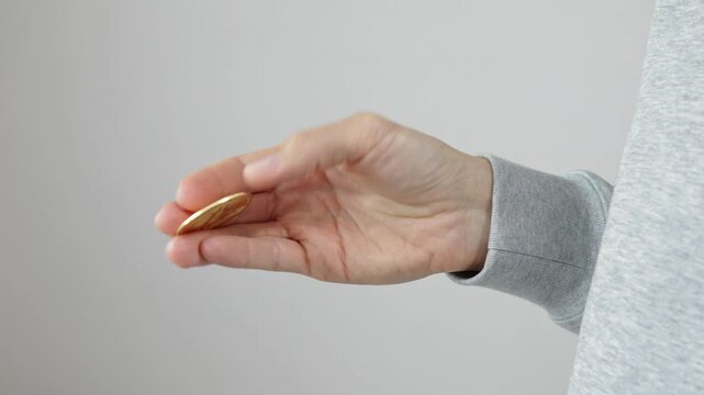 Hand spinning bitcoin coin on light background, cryptocurrency trading, blockchain technology, digital finance and virtual money concept.
