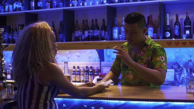 Transgender woman discussing with a bartender while holding a receipt at a nightclub counter