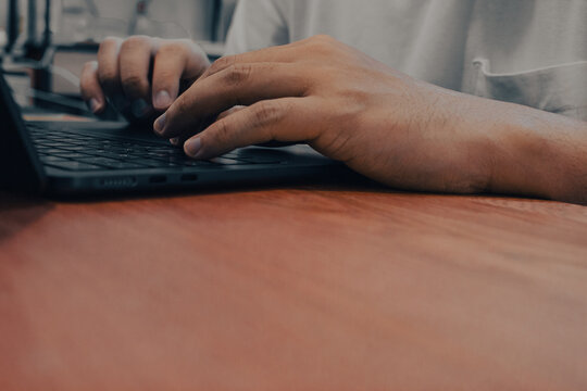 Close-Up of Hands Typing on Black Laptop Keyboard on Wooden Desk, Business Work from Home Concept