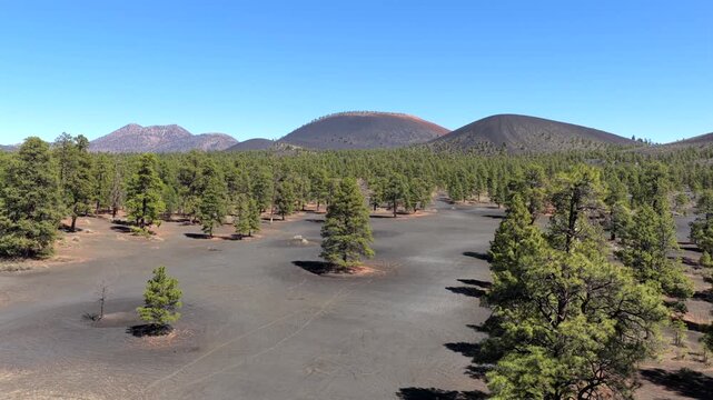 4K drone perspective captures volcanic cinder cone and geologic scoria formation in Arizona pine forest. High altitude aerial view reveals volcanic geography and southwestern desert topography.