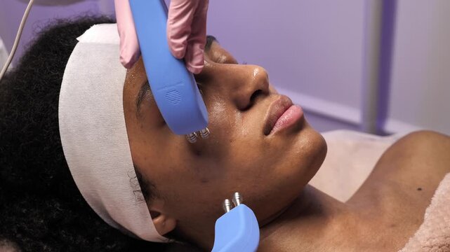 Extreme close up of microcurrent electrodes on African American woman's face. Professional lifting procedure for skin tightening and rejuvenation.