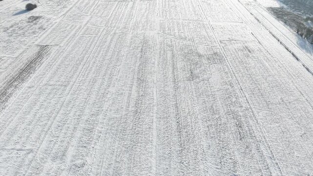Rural winter agriculture field with tractor marks