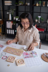 Fototapeta premium Mature asian woman&nbsp;making handmade jewellery accessories handcraft hobby