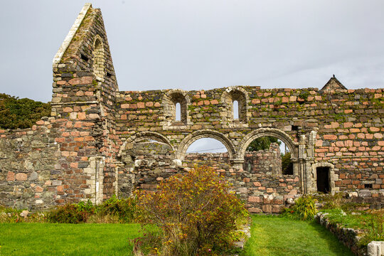 View of the ancient stone ruins and Romanesque arches of Iona Nunnery under an overcast sky in Baile Mor, Scotland, United Kingdom.