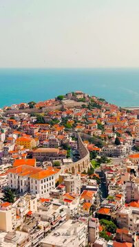 Vertical video. Kavala, Greece. Kavala Fortress and Aqueduct. The ferry leaves the port. Historic city center. Summer. Drone footage. Rich colors