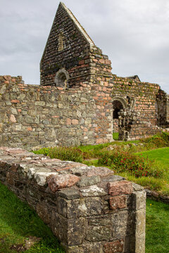 View of Iona Nunnery ruins with ancient stone walls and arched windows under a cloudy sky in Baile Mor, Scotland, United Kingdom.