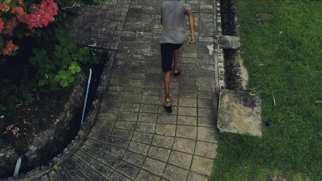 Aerial view of a person escaping by squeezing through a broken fence and running away