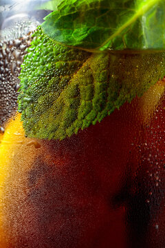 Cocktail with lemon, ice and mint in misted glass.