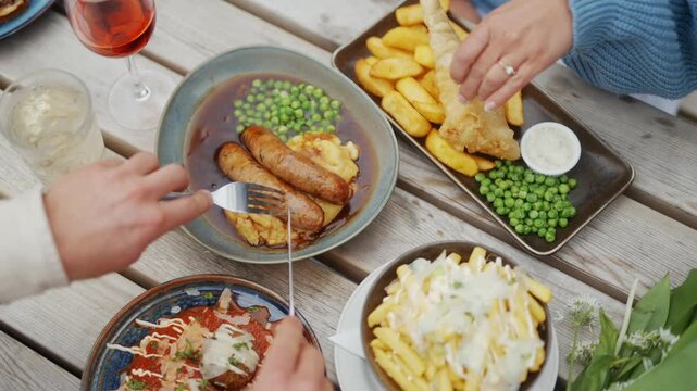 People Enjoying Traditional Pub Food Outdoors on a Wooden Table