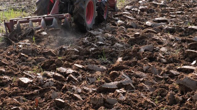 A tractor is working in a rice field, preparing the soil before planting rice. (Concept)