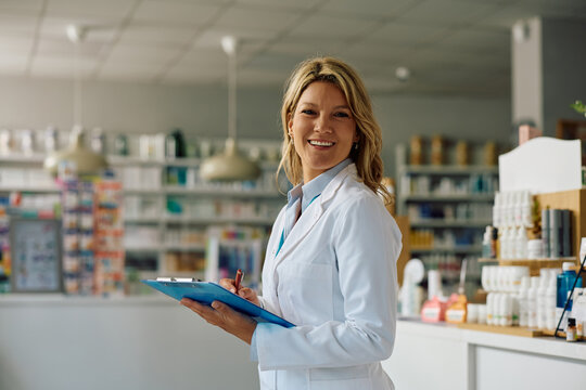 Happy pharmacist working in drugstore and looking at camera.