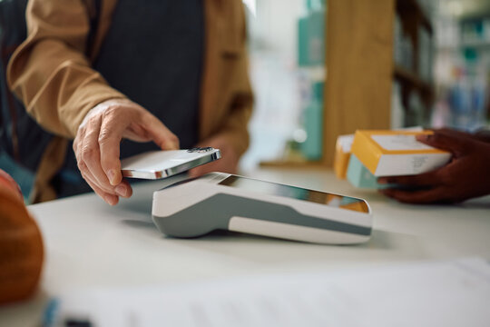 Close up of man paying with mobile phone app on pharmacy.