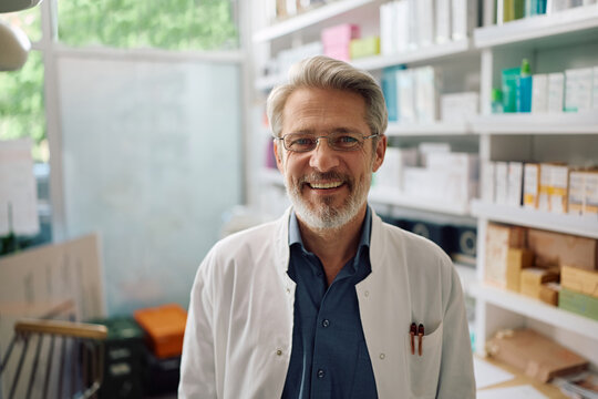 Happy mature pharmacist at work looking at camera.