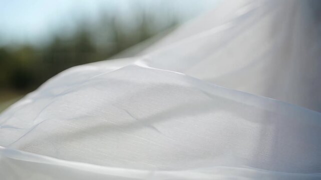 Close up of elegant white wedding veil blowing in the wind.