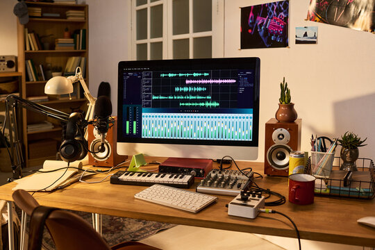 Home recording studio displaying audio editing software on desktop monitor with microphone, headphones, mixer, keyboard. Supporting podcast production, music creation, creator marketing