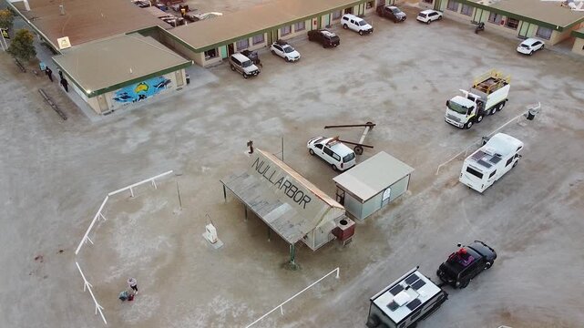 An overhead shot of the Nullarbor Roadhouse with parked vehicles and a surrounding barren landscape. Suitable for travel documentaries or Australian outback features.